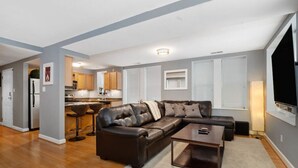 Una sala de estar moderna con un sofá seccional, una mesa de centro y un televisor.