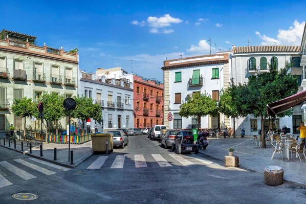A street view with buildings, parked cars, and a pedestrian crossing. - DescubreHome Macarena Town Center (Sevilla)