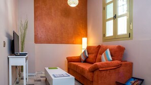 A living room with a sofa, a coffee table, a TV, and a lamp. - DescubreHome Macarena Town Center (Sevilla)
