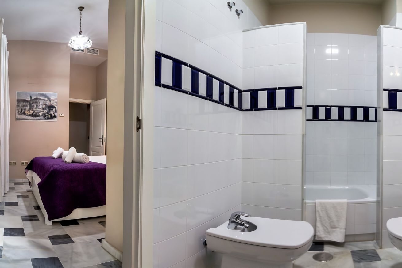Une salle de bain avec des carreaux blancs, une baignoire, des toilettes et un lavabo.