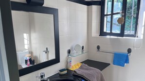 Ein Badezimmer mit einem schwarzen Waschbecken, einem Spiegel, einer Toilette und einem Fenster mit einer Rosendekoration.