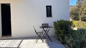 Ein weißes Gebäude mit einem kleinen Fenster, einer Tür und einem Tisch mit Stuhl davor.