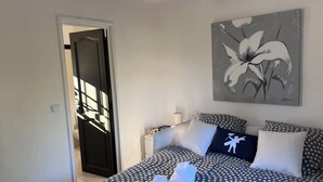 Ein Schlafzimmer mit Bett, Kissen, einem Gemälde und einer Tür.