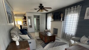 Un salón espacioso con un sofá gris, una mesa de centro de madera y una chimenea.