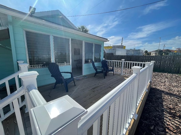 A house with a covered porch, two chairs, and a white railing.