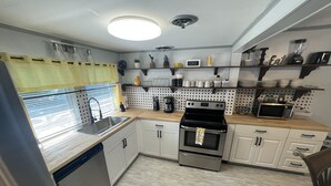 Una cocina moderna con electrodomésticos de acero inoxidable, armarios blancos y encimera de madera.