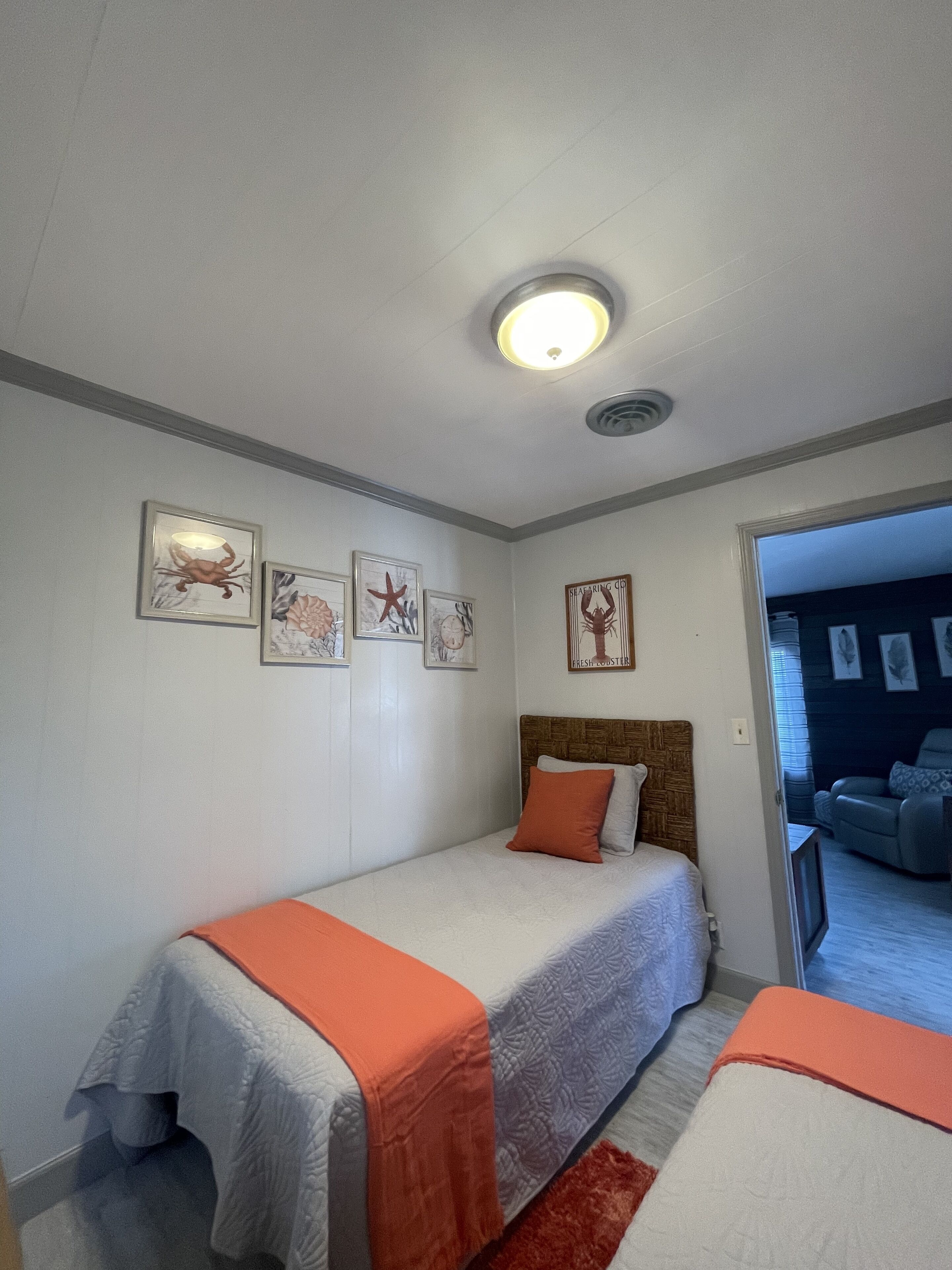 A bedroom with two beds, a wooden headboard, and a ceiling light.