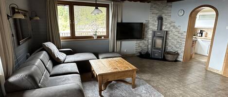 A modern living room with a sectional sofa, a wooden coffee table, a TV, and a stone fireplace.