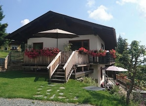 A two-story building with a balcony, a wooden deck, and a staircase leading to the upper floor.