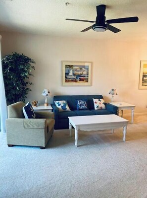 Relax in this inviting living room with a beige armchair, dark blue sofa, and a cozy coffee table.