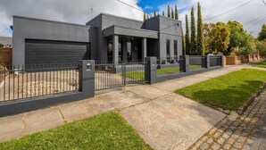 Une maison moderne à deux étages, dotée d’un garage, d’une allée bordée d’une clôture et d’une pelouse bien entretenue.