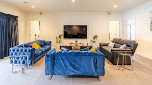 Un salon moderne avec un grand téléviseur à écran plat, deux canapés et une table basse.