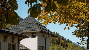Un chalet traditionnel doté d’un toit à pente, de poutres en bois et d’une façade blanche.