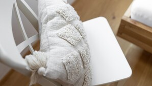 Une chaise blanche avec un coussin décoratif blanc à texture.