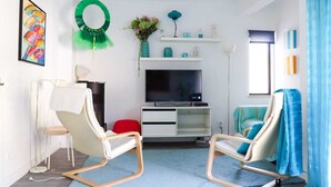 A modern living room with a flat-screen TV, two rocking chairs, a red chair, a white cabinet, and a green wreath on the wall. - Charming and comfortable 380 m from the beach (Nazare)