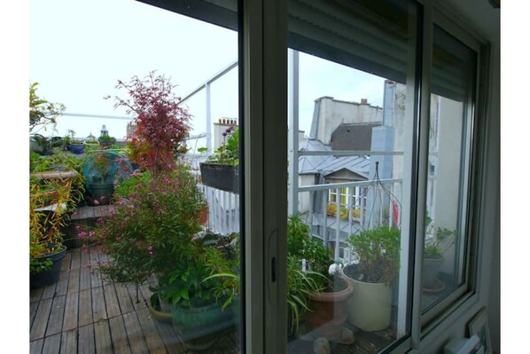 A balcony with potted plants and a view of neighboring buildings.