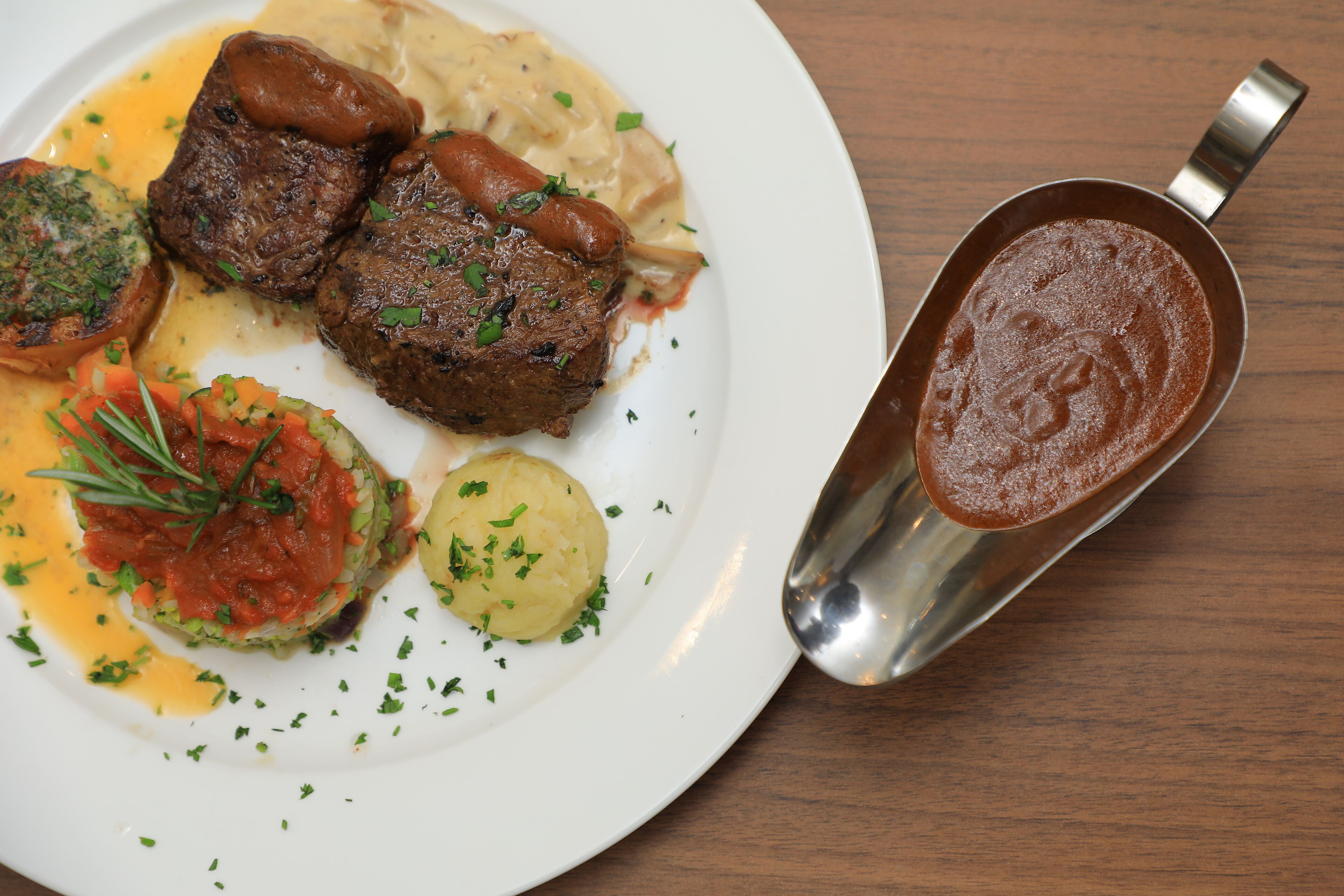 A plate of food with steak, mashed potatoes, and a sauce.