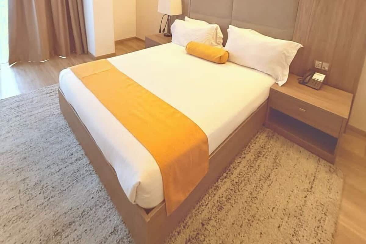 A hotel room with a large bed, a bedside table with a lamp, and a phone.