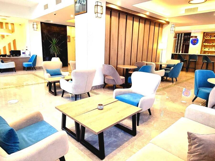 Um saguão de hotel com áreas de estar, balcão de recepção e um bar.