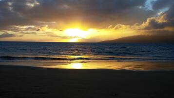 Una playa con el sol poniéndose sobre el océano, creando un ambiente tranquilo y sereno.