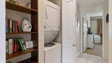 A laundry room with a washing machine and dryer, a bookshelf with books, and a hallway leading to a bathroom.