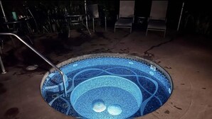 Un jacuzzi rond orné de motifs en mosaïque, entouré d’une terrasse en béton.