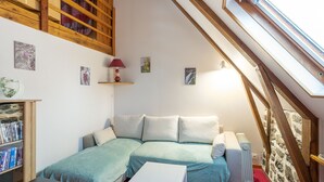 A cozy attic bedroom with a loft bed, a small table, a radiator, and a bookshelf. - Gite Les Marmottes - Two Bedroom House, Sleeps 5 (Trémouille)