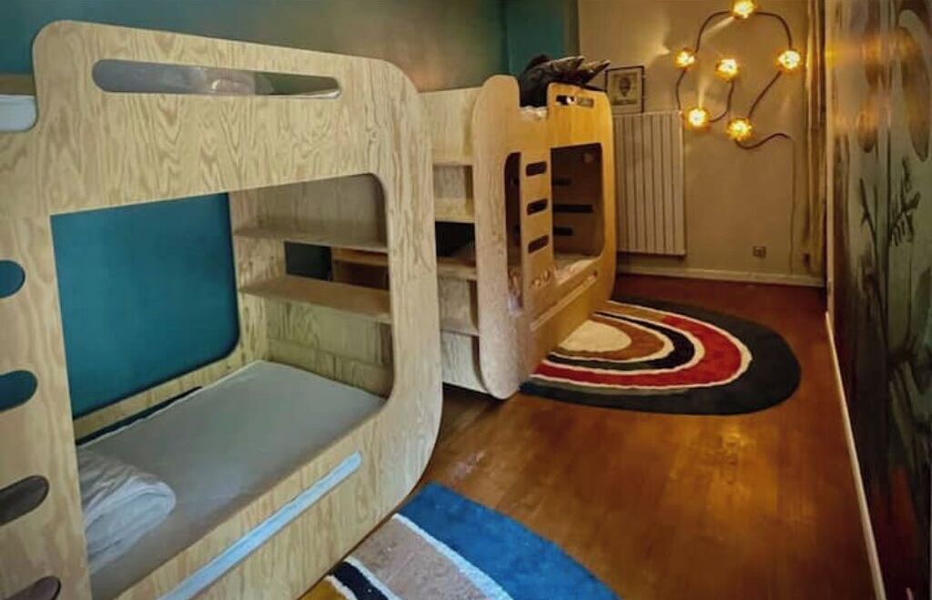 Ein Zimmer mit einem Etagenbett, einem kleinen Tisch und einer Heizung.