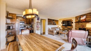 Amplia sala de estar con una mesa de comedor de madera, un sofá de cuero y una chimenea de piedra.