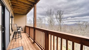 Una terraza de madera con vistas a montañas y árboles.
