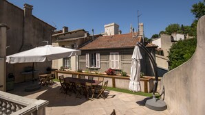 An outdoor patio with a table and chairs, a grill, and a white umbrella. - A L'OMBRE DU PALAIS (Avignon)