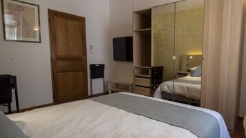 Una habitación de hotel con una cama grande, un armario, un televisor y un espejo.