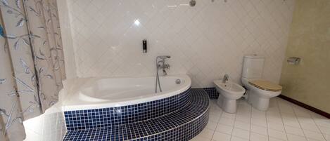 A bathroom with a freestanding bathtub, a bidet, and a toilet.
