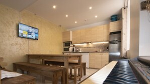 A kitchen with wooden cabinets, a built-in microwave, a coffee maker, and a refrigerator. - A L'OMBRE DU PALAIS (Avignon)