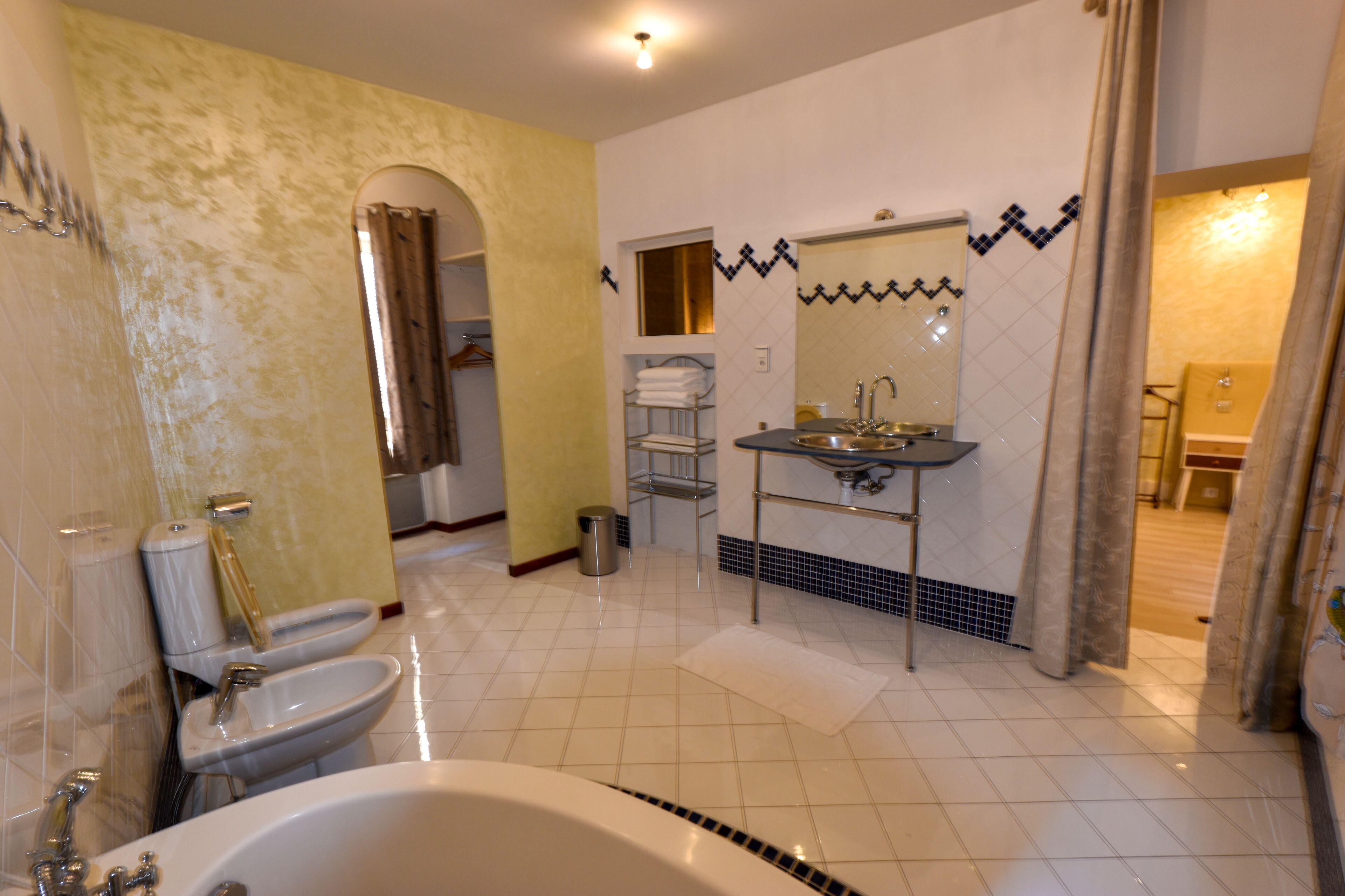 Een badkamer met een badkuip, twee wastafels en een douche.