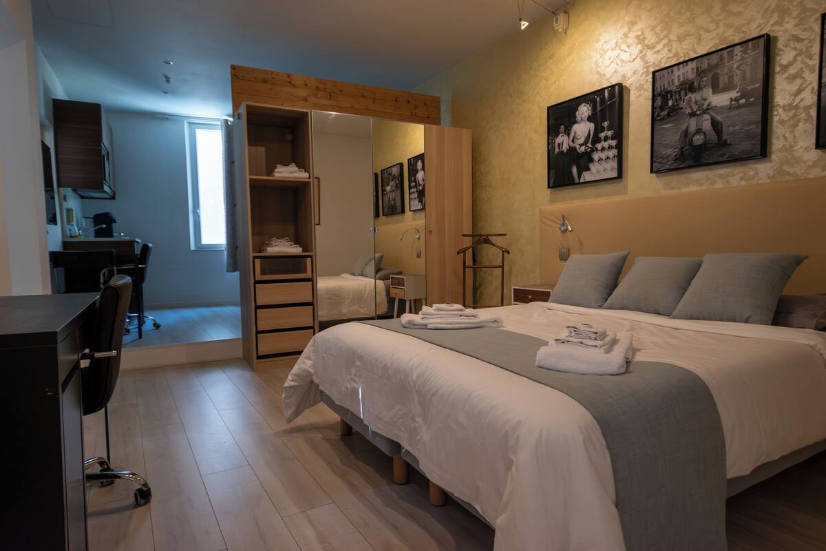 A bedroom with a bed, a desk, a wardrobe, and a bathroom.