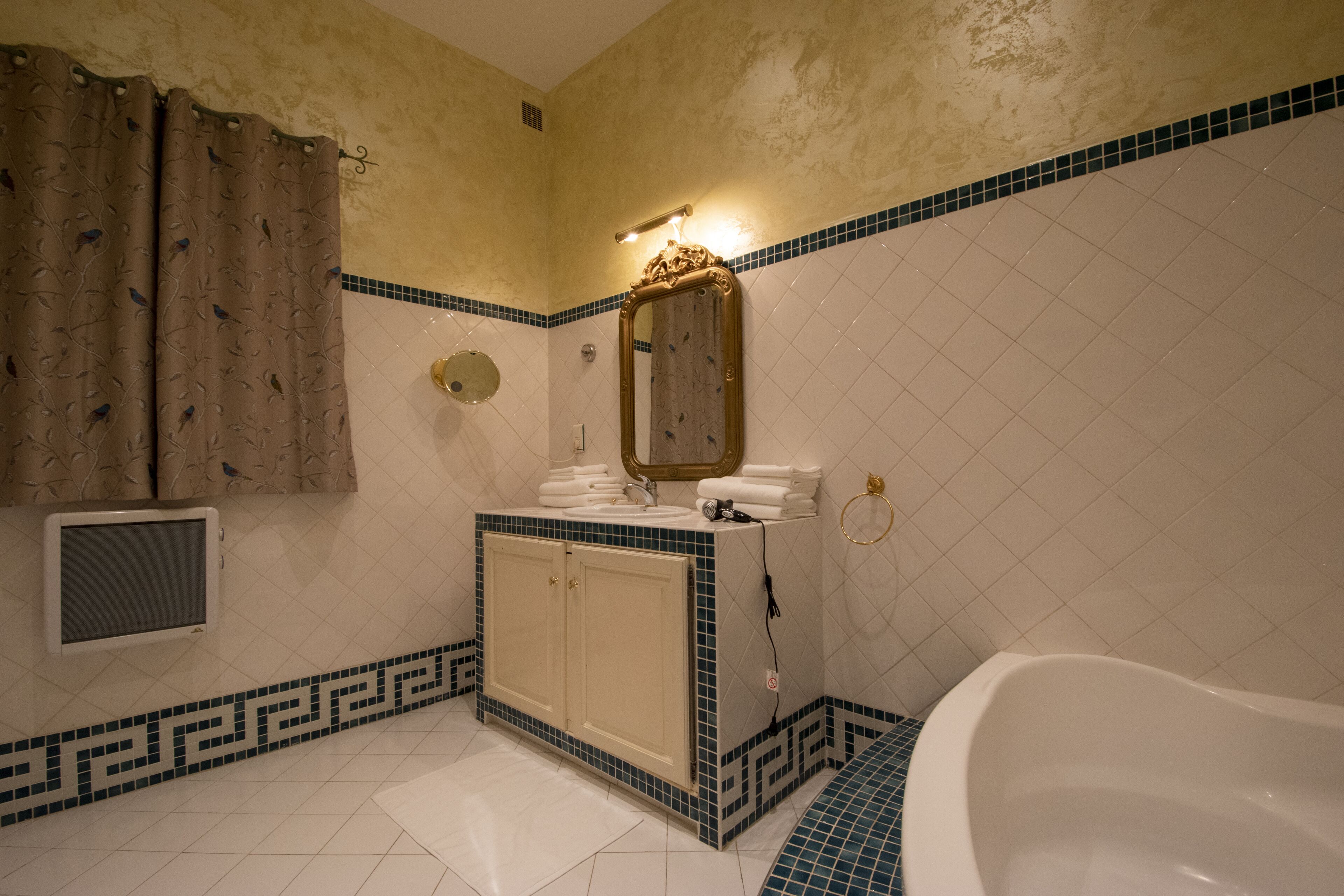 Ein Badezimmer mit einer Badewanne, einem Waschtisch inklusive Spiegel und einer Dusche.