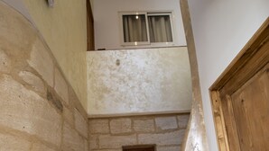 A narrow staircase with stone walls and wooden steps, leading to a room with a window and a door. - A L'OMBRE DU PALAIS (Avignon)