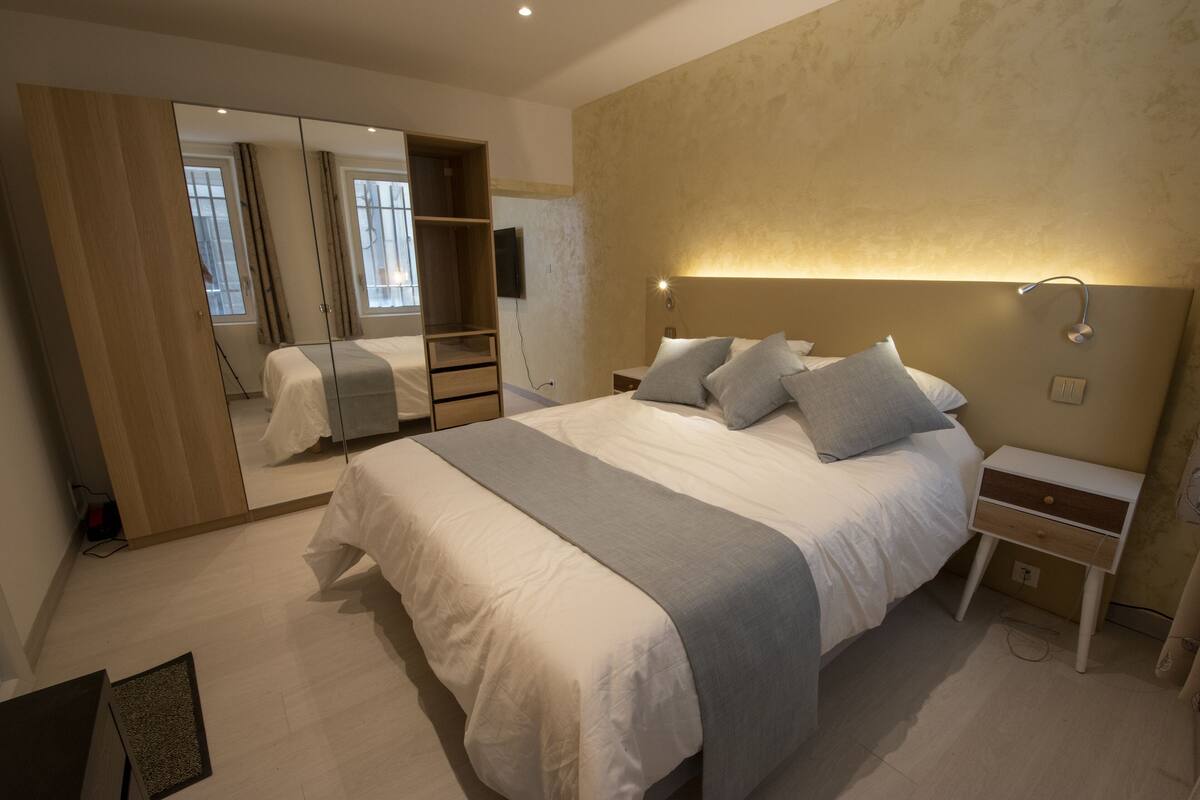 A bedroom with a large bed, bedside tables, a mirror, and a wardrobe.