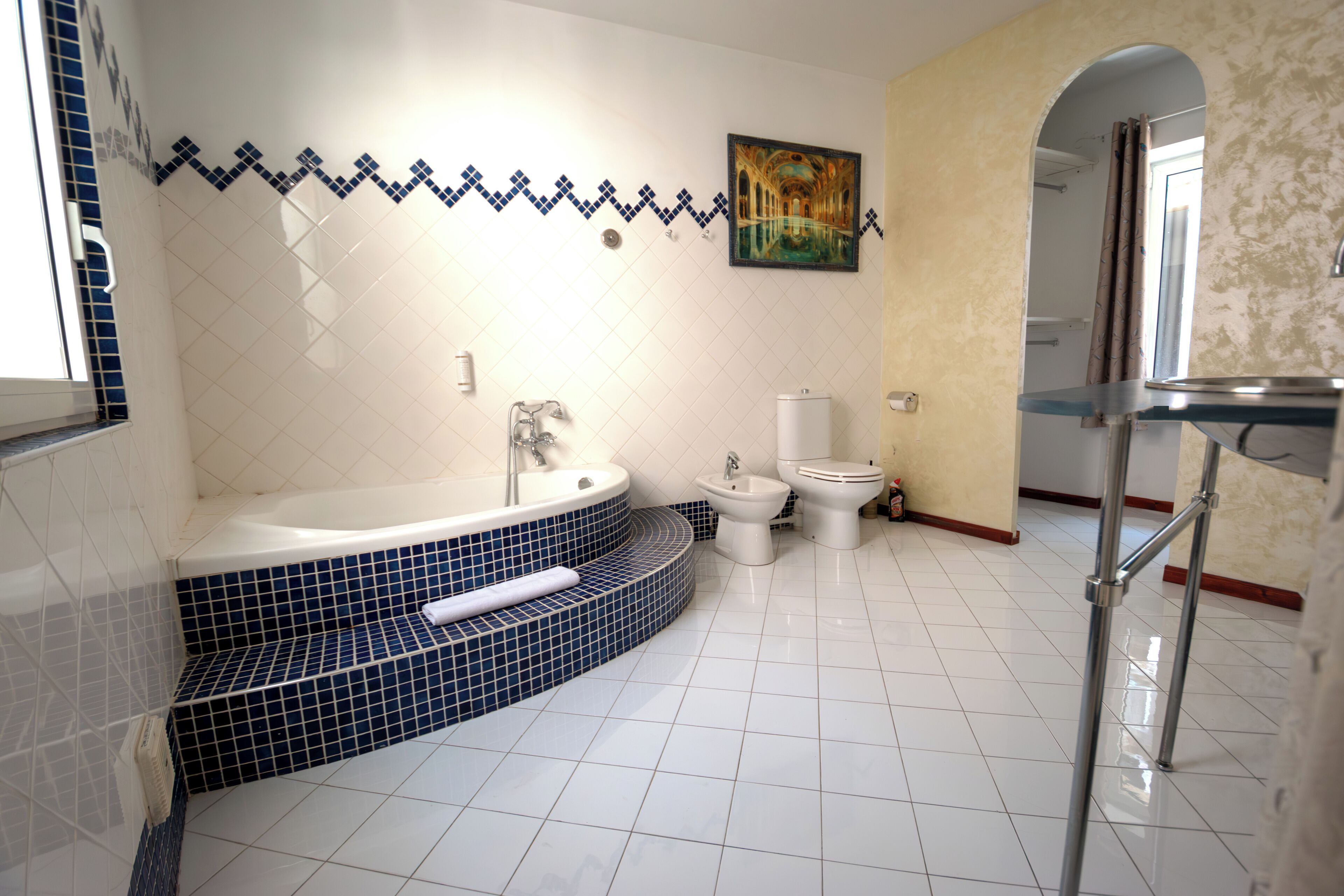A bathroom with a bathtub, two toilets, and a sink.