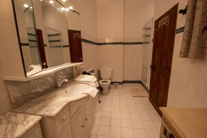 A bathroom with a marble sink, a toilet, and a shower area.