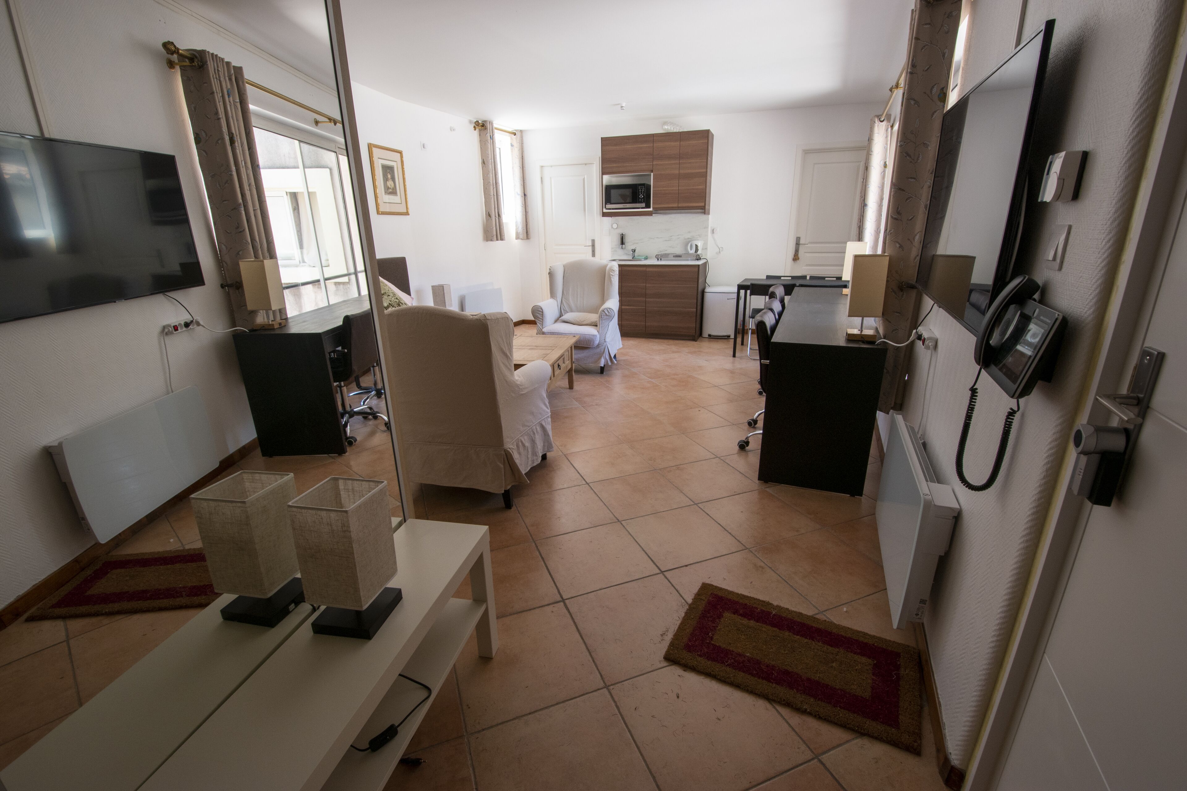 Hotelkamer met televisie, bed, bureau, stoel, magnetron, telefoon en een kitchenette.