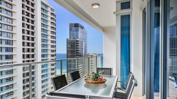 A balcony with a table and chairs, overlooking a cityscape and the ocean. - Bliss By The Ocean beautiful views, walk to beach! (Surfers Paradise)