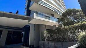 A modern building with a glass facade, a water feature, and a palm tree. - Bliss By The Ocean beautiful views, walk to beach! (Surfers Paradise)