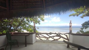 A balcony with a view of the sea, a wooden fence, and a chair. - Villa Valiha Lodge (Nosy Be)