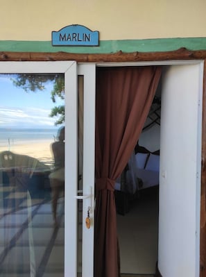 Une chambre avec vue sur la mer, un lit et une porte avec un rideau.