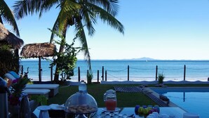 An outdoor dining area with a view of the ocean, a pool, and a buffet setup. - Villa Valiha Lodge (Nosy Be)