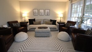 A modern bedroom with a large bed, two side tables with lamps, a sofa, and a patterned rug. - Charming 3-Bedroom Retreat with Private Yard (Charleston)