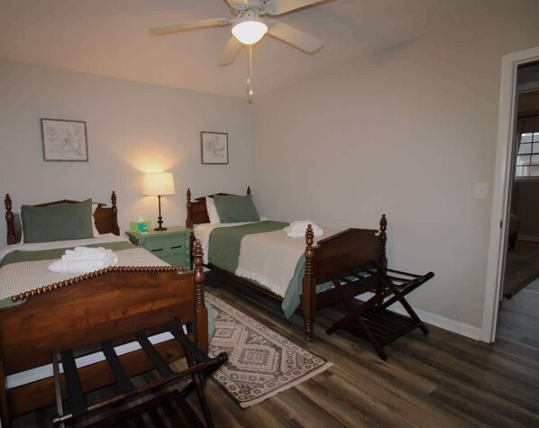 A bedroom with two wooden beds, a ceiling fan, and a nightstand with a lamp.