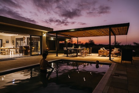 Una piscina al aire libre, sombrillas, sillones reclinables de piscina